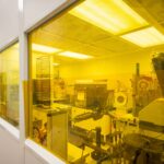 Cleanroom with machines viewed through yellow-tinted photolithography-safe window.