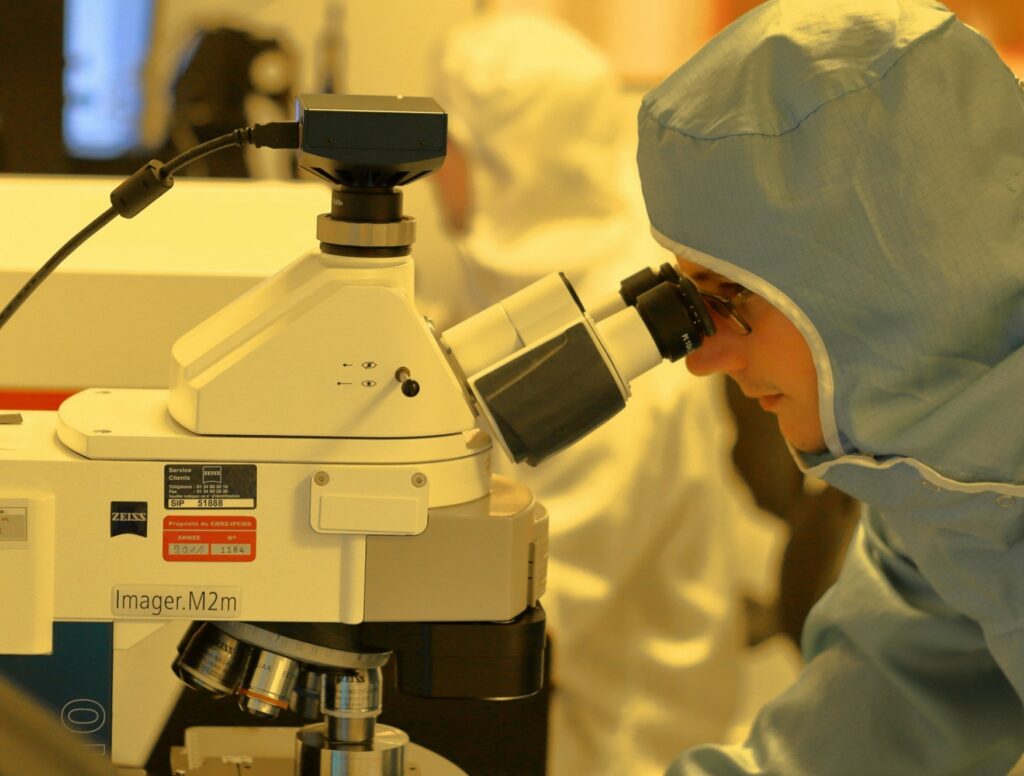 Scientist in cleanroom suit using ZEISS Imager.M2m microscope in sterile lab environment.
