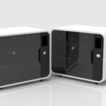 Two enclosed prototype units with tinted front panels and internal racks, side-by-side in clean lab setting.